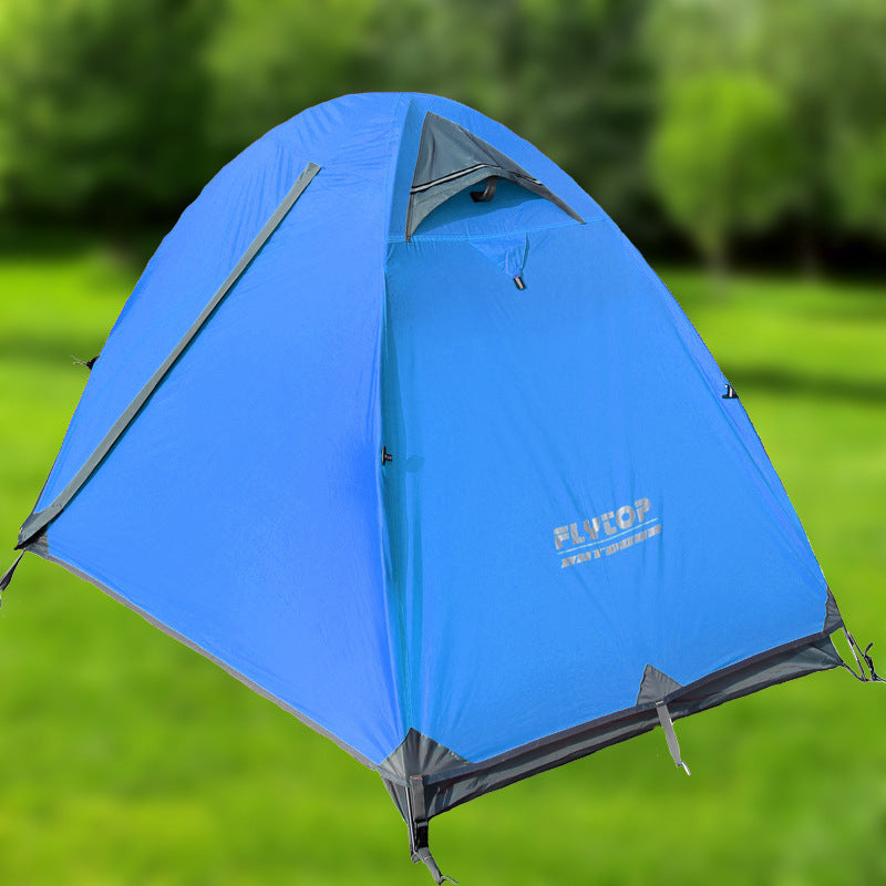A bright blue eprolo Outdoor Double Camping Rainproof Tent is set up on grassy terrain with trees in the background. This ultra-light mountaineering tent has a triangular flap partially open at the front, showcasing its high-altitude design.