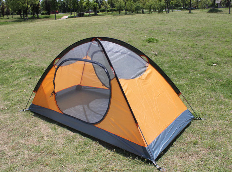 An eprolo Outdoor Double Camping Rainproof Tent, in orange and gray, is set up on a grassy field under bright sunlight. Trees and a walkway are in the background, highlighting its versatility for both parks and high-altitude mountaineering.
