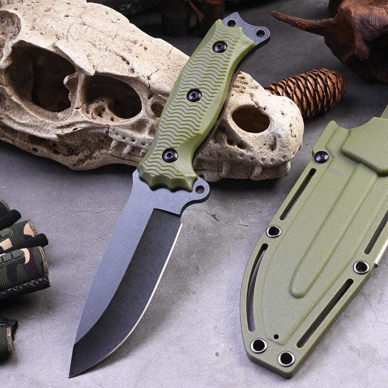 The eprolo A3 High Hardness Outdoor Multifunctional Portable Knife, featuring an olive green handle and black blade, rests on a gray surface with its matching sheath. Animal skulls and a pinecone in the background highlight its versatility as a survival tool.
