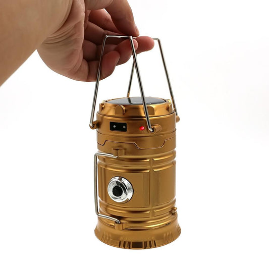 The eprolo LED Hand Lamp Rechargeable Collapsible Solar Camping Lantern, in gold, has a hand lifting the metal handle. It features a top solar panel, red indicator light button, and side round light, making it perfect for emergency kits.