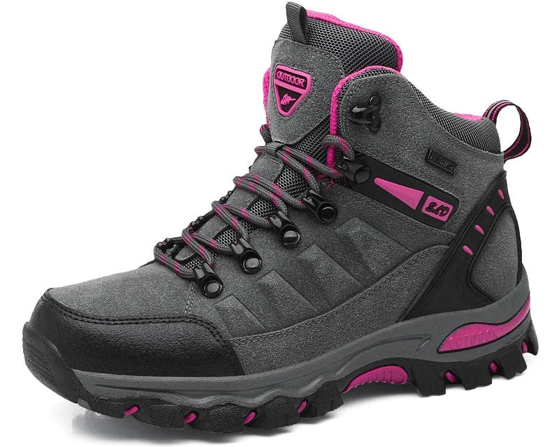 The Women’s Winter Trekking Boots by Ten Essentials are durable hiking shoes in grey with black and pink details, rugged soles, sturdy laces, branding on the side and top, and a convenient back loop—ideal for outdoor adventures.