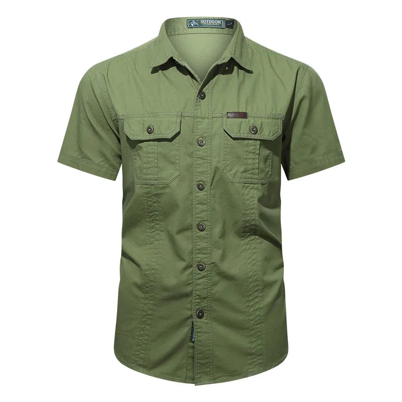 The Men’s Quick-Dry Tactical Shirt by Ten Essentials is a green, military-inspired short-sleeved shirt with two buttoned flap chest pockets, crafted from breathable cotton fabric and featuring a collar with a subtle logo tag above the left pocket.