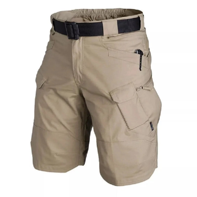 The Men’s Tactical Cargo Shorts by Ten Essentials are waterproof and feature a multi-pocket design with a zippered pocket on the right. They are made from lightweight, breathable fabric and include an elastic waistband with a black belt, all showcased on a plain white background.
