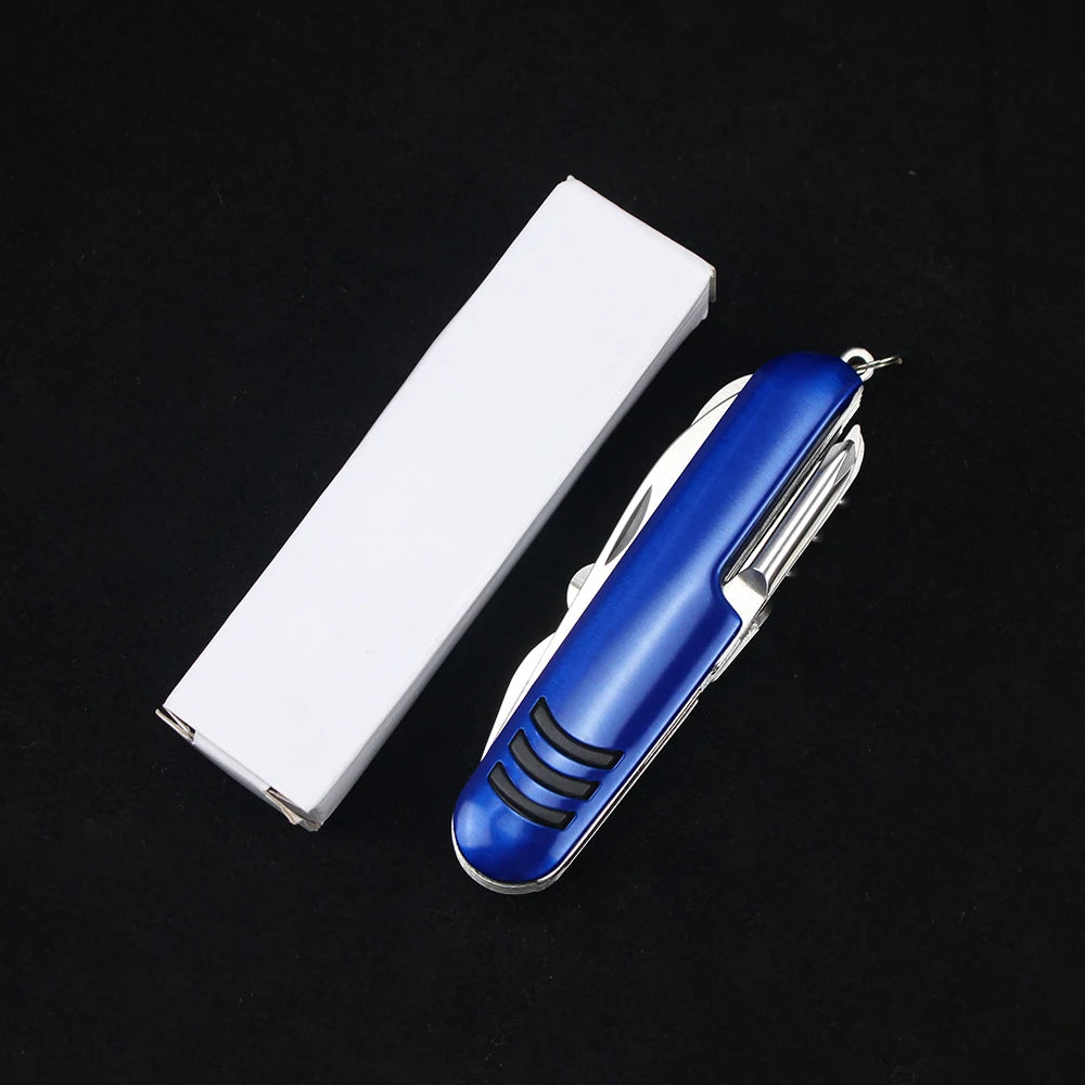 The Ten Essentials 11-in-1 Swiss Folding Pocket Knife with a blue handle sits next to a closed white box on a black surface. Made from stainless steel, this multitool features various foldable tools for any task.