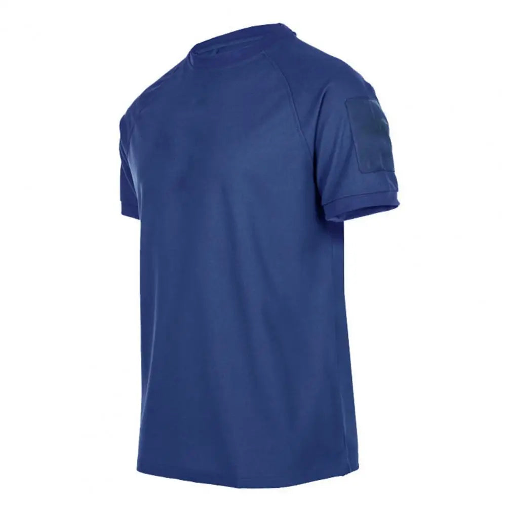 The Men’s Quick-Dry Military T-Shirt by Ten Essentials is displayed on a white backdrop from the side. This plain blue shirt features short sleeves and a round neck, crafted with lightweight, breathable, and moisture-wicking fabric for simple, casual comfort.