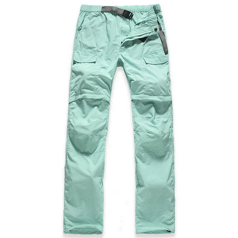The NUONEKO Women’s Convertible Hiking Pants by Ten Essentials are light green, with multiple pockets, a dark belt, quick-dry fabric, knee stitching, and a zipper fly. Ideal for adventures, they are laid flat on a white background to showcase their features.