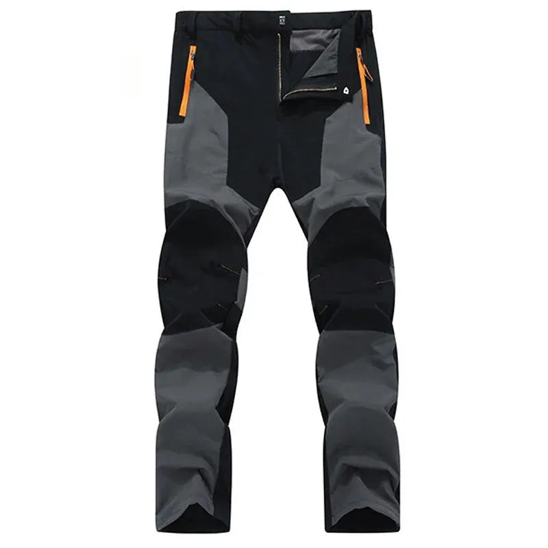 The Ten Essentials Men’s Quick-Dry Hiking Pants, in a black and dark gray two-tone, feature ultra-stretch fabric, orange zippered pockets, reinforced knees, UV protection, and water resistance for ultimate comfort on outdoor adventures.