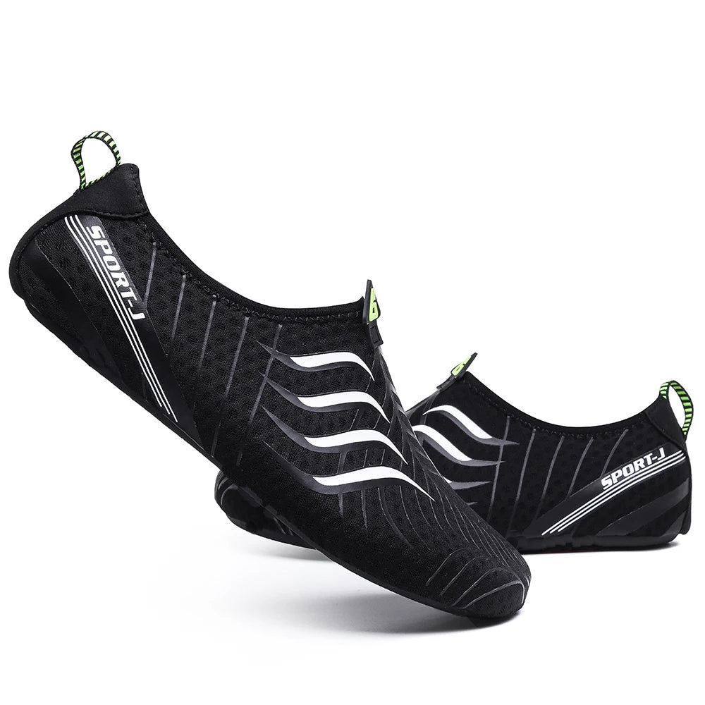 A pair of Ten Essentials Men’s Breathable Mesh Sneakers in black, with white wavy lines and a SPORT-I logo, featuring quick-dry fabric and green heel pull tabs. These lightweight non-slip hiking shoes offer a sporty design on a white backdrop.