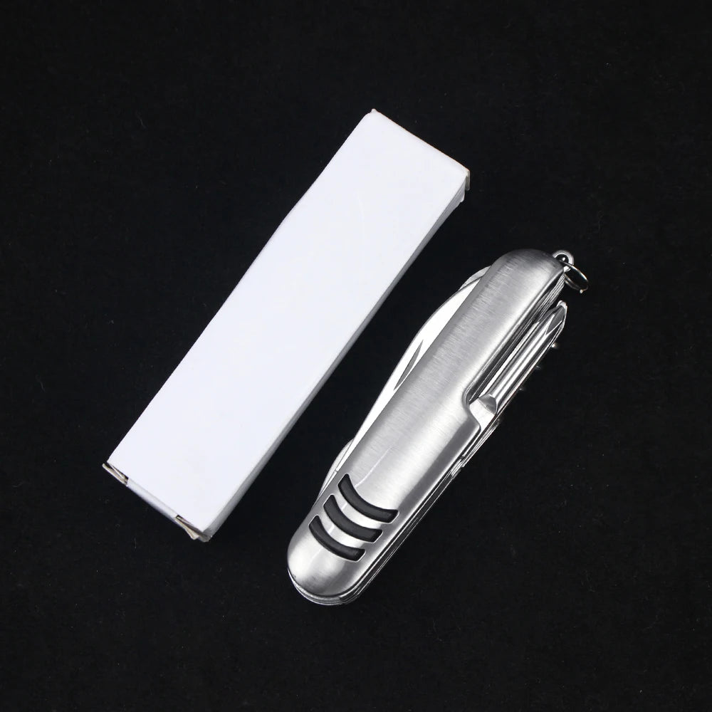 The 11-in-1 Swiss Folding Pocket Knife by Ten Essentials, featuring a sleek stainless steel design, is placed next to a plain white rectangular box on a stark black background.