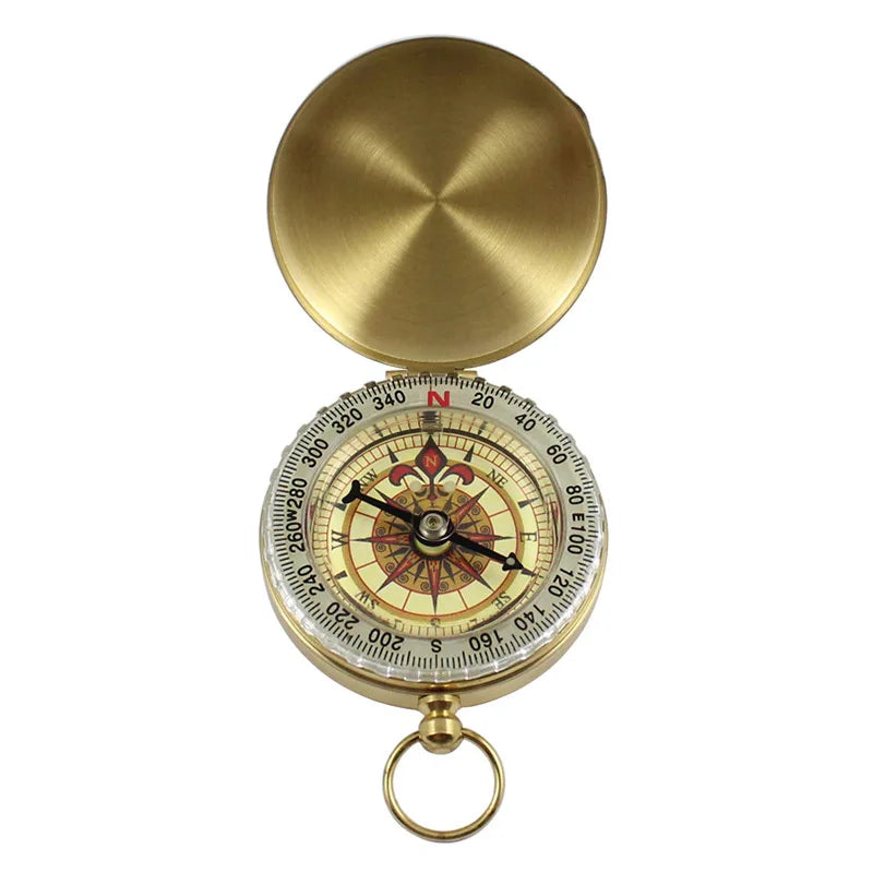 The Ten Essentials Portable Water-Resistant Luminous Brass Compass features a hinged lid open to a rose design, ideal for outdoor adventures. It has a north-pointing needle and a small loop for easy carrying. The polished lid adds elegance to this survival staple.