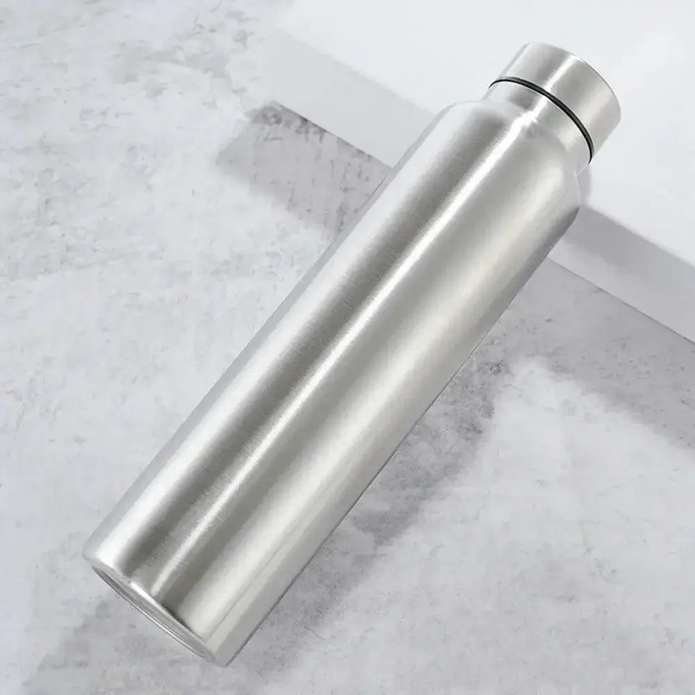The 1000ml Stainless Steel Sports Water Bottle by Ten Essentials, eco-friendly with a black ring around the cap, sits on a textured gray surface. Its smooth cylindrical shape and minimalist design make it both stylish and sustainable.