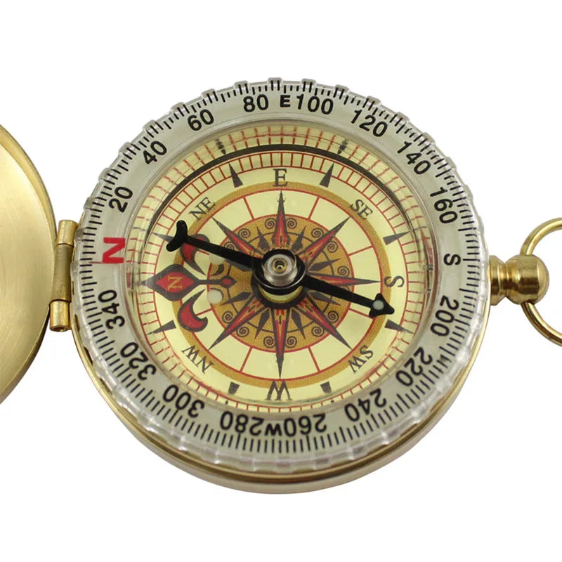 The Ten Essentials Portable Water-Resistant Luminous Brass Compass, featuring a detailed dial with cardinal and intercardinal directions, is ideal for outdoor adventures. Its intricate center patterns and north-pointing needle make it an essential tool for survival situations.