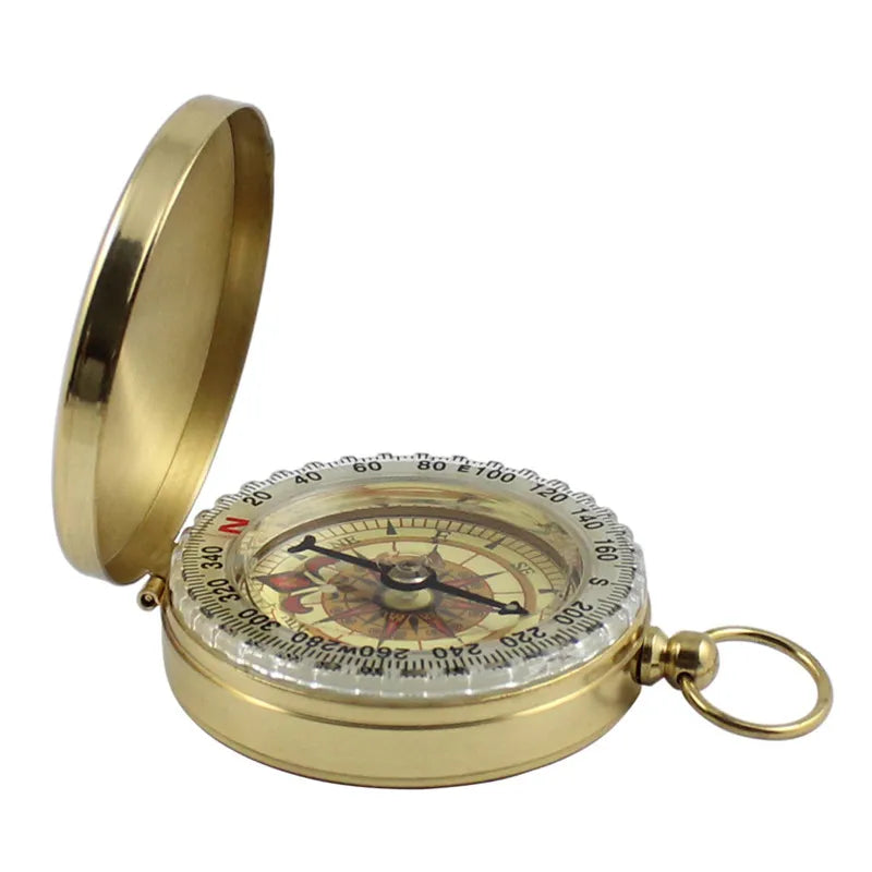 The Ten Essentials Portable Water-Resistant Luminous Brass Compass, shown open with a vintage design, is great for outdoor adventures. Its needle points north, and an attached ring ensures easy carrying. Cardinal directions and degree markings make it ideal for survival scenarios.