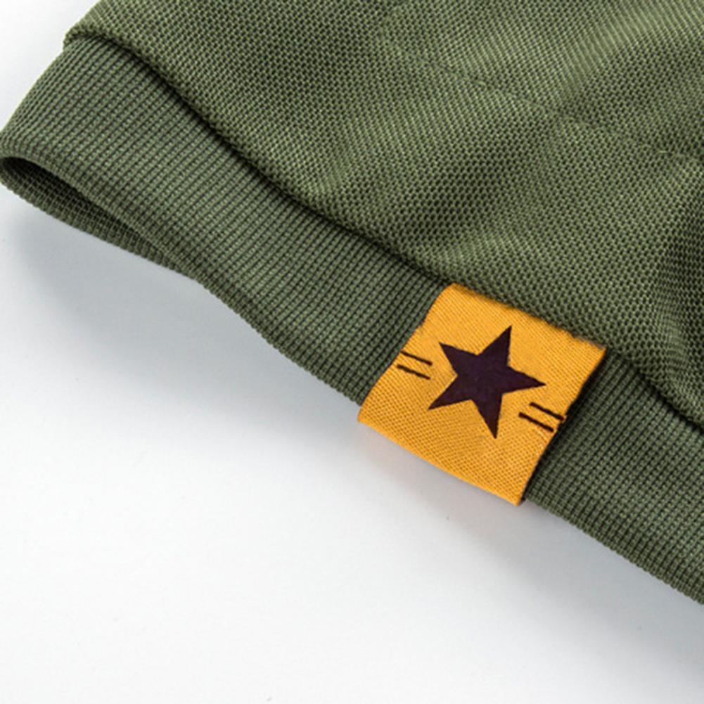 Close-up of a textured green fabric with a folded edge, featuring Ten Essentials yellow tag with a black star. This resembles the design of the Men’s Quick-Dry Military T-Shirt—lightweight, breathable, and moisture-wicking. The background is solid light-colored.
