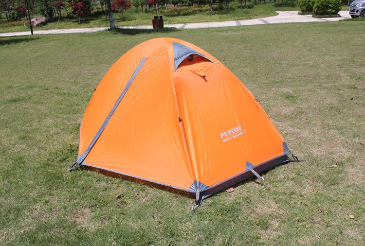 The eprolo Outdoor Double Camping Rainproof Tent, featuring an orange design with gray trim, is set up on park grass. This ultra-light high mountain snowfield camping equipment provides the ideal mix of nature and shelter under a clear sky amid greenery and walkways.
