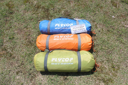 Three rolled-up Outdoor Double Camping Rainproof Tents in blue, orange, and green rest on the grass. Each ultra-light tent, perfect for high-altitude mountaineering in snowfields, features the brand name eprolo emblazoned in white lettering.