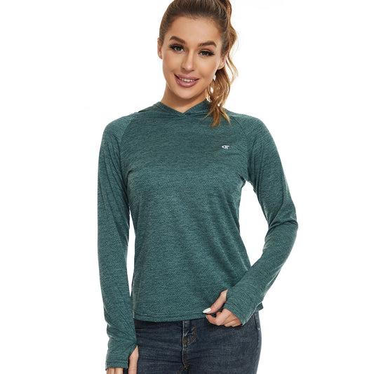 A person wearing Ten Essentials Womens UPF 50+ Sun Protection Hoodie in teal with blue jeans stands against a white background. Their long hair is styled in a ponytail, and they smile at the camera with one hand on their waist.