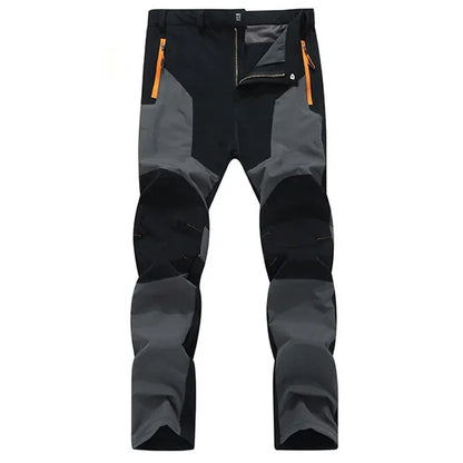 The Ten Essentials Men’s Quick-Dry Hiking Pants, in a black and dark gray two-tone, feature ultra-stretch fabric, orange zippered pockets, reinforced knees, UV protection, and water resistance for ultimate comfort on outdoor adventures.