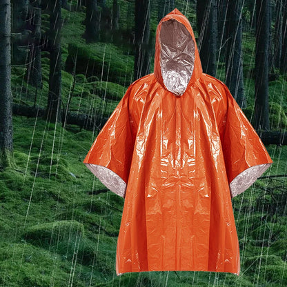 The Ten Essentials Emergency Rain Poncho, featuring a Mylar blanket liner, is displayed against a lush green forest. This heavy-duty waterproof survival gear includes heat retention technology and wide sleeves for maximum protection, keeping you warm and dry in emergencies.