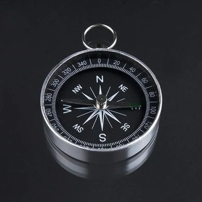 The Portable Aluminum Emergency Compass by Ten Essentials is a lightweight survival navigation tool featuring a silver aluminum frame, black face, fluorescent pointers for visibility, cardinal directions with degree markings, and a reliable north-pointing needle—a crucial outdoor accessory.