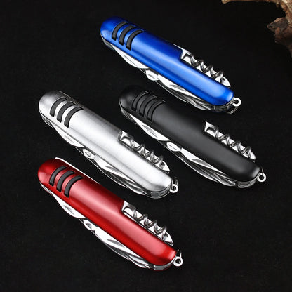 Four Ten Essentials 11-in-1 Swiss folding pocket knife multitools in red, silver, blue, and black are displayed on a dark surface. Each features ridged grips and multiple fold-out stainless steel tools in a compact design reminiscent of a Swiss Army knife.