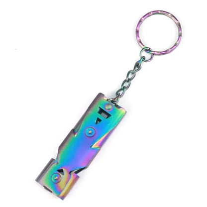 The High-Decibel Double Pipe Survival Whistle by Ten Essentials is a portable keychain with robust construction and vibrant rainbow metallic surface, featuring an attached folding box cutter on a metal ring for emergencies.