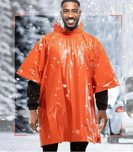 A man dons a Ten Essentials Emergency Rain Poncho with Mylar Blanket Liner in a snowy landscape. A cars trunk is open in the background. The text reads, Prepare for the Unexpected with Heat Retention Technology. Ready for Anything the Road May Bring.