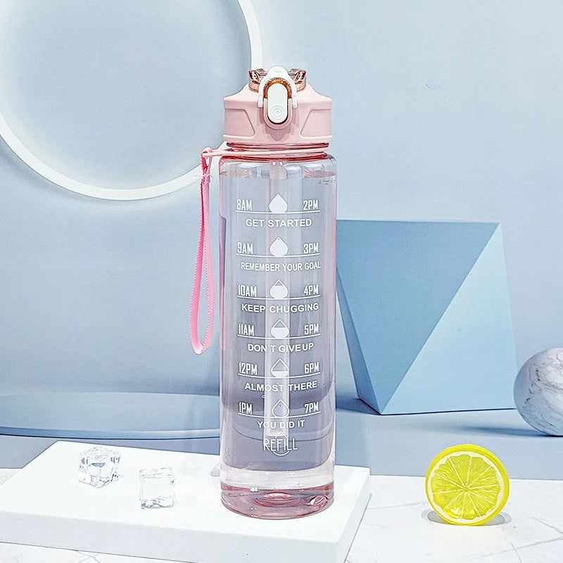 The Ten Essentials Sports Water Bottle (750-800ML) features a pink lid, strap, time-tracking straw with motivational goals from 8 AM to 8 PM. Seen on a white podium with lemon slice and geometric shapes in the backdrop, its perfect for hydration on the go.