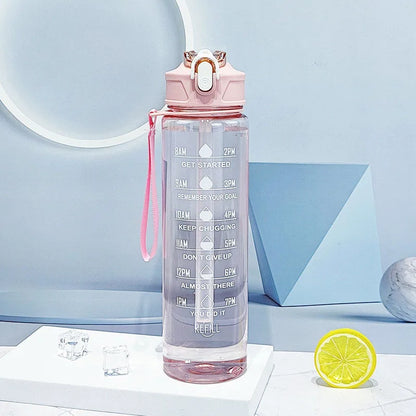 The Ten Essentials Sports Water Bottle (750-800ML) features a pink lid, strap, time-tracking straw with motivational goals from 8 AM to 8 PM. Seen on a white podium with lemon slice and geometric shapes in the backdrop, its perfect for hydration on the go.